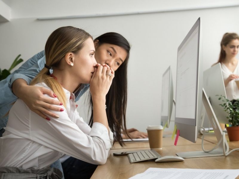 Asian colleague embracing supporting caucasian woman