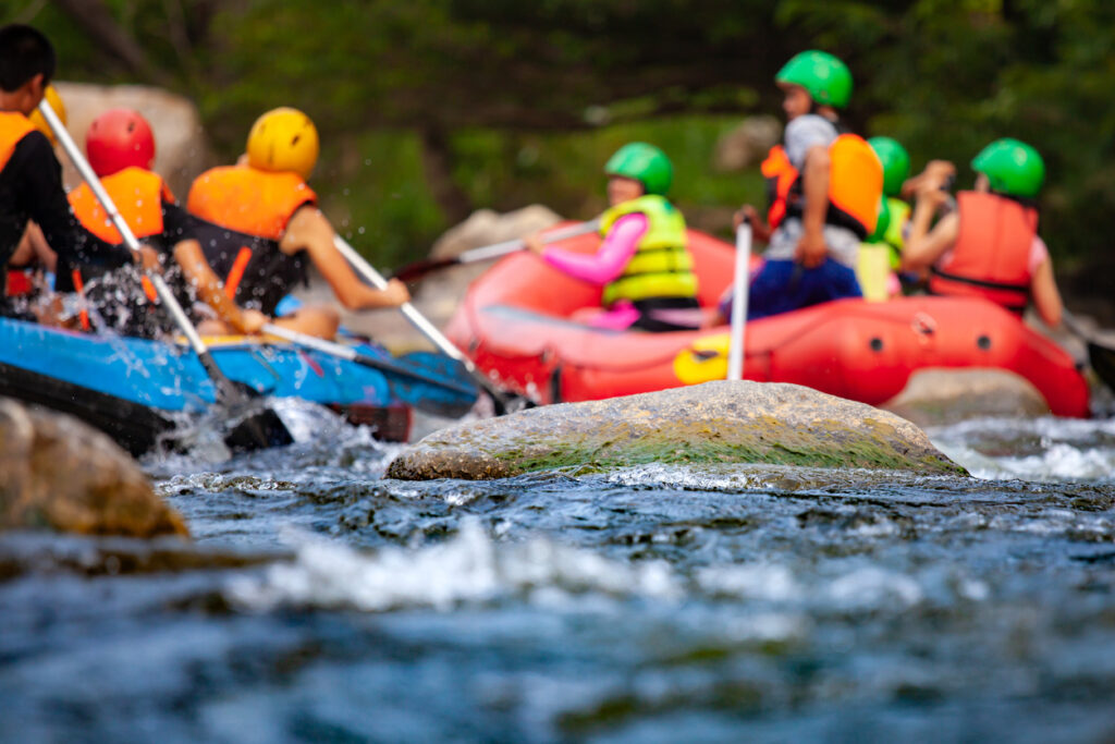 Close-up of reef with group of young people are rafting on the river, at tourist attraction.