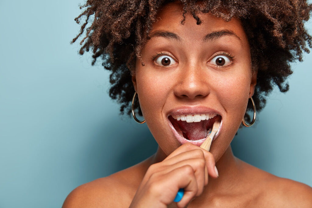 Young woman with a bright smile brushing her teeth