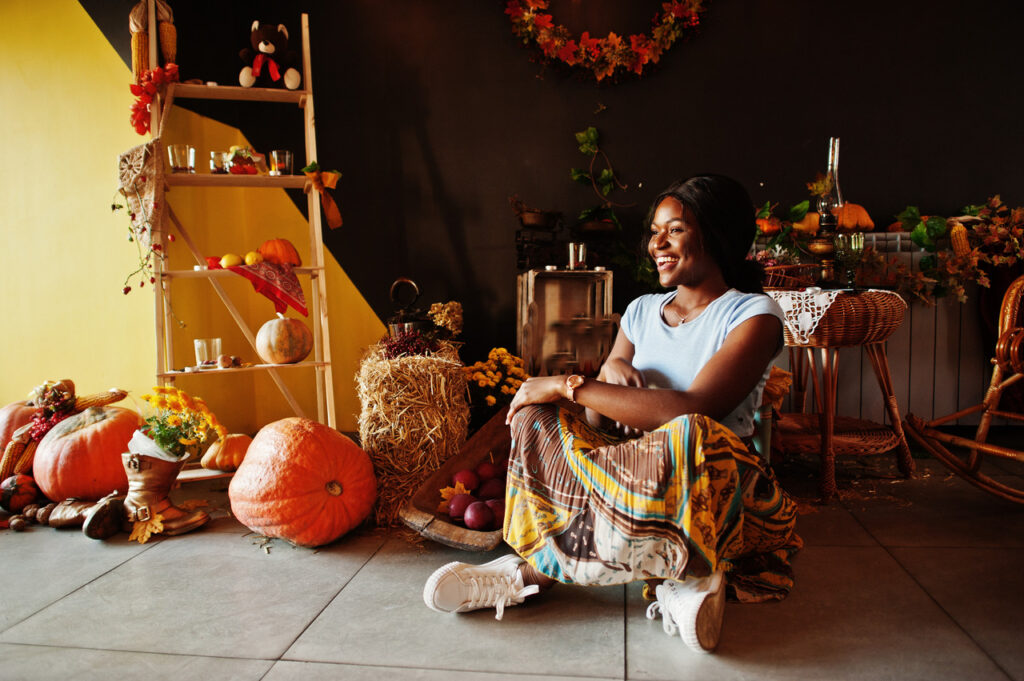 A woman sits on the fall surrounded by fall-themed decorations