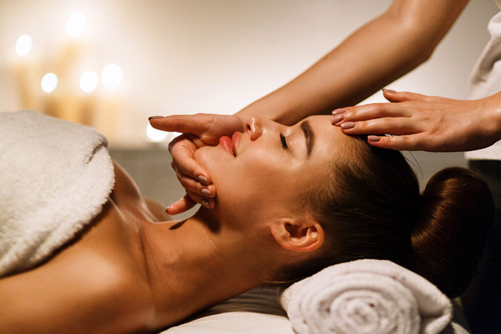 Woman enjoying anti aging facial massage in atmospheric spa, side view