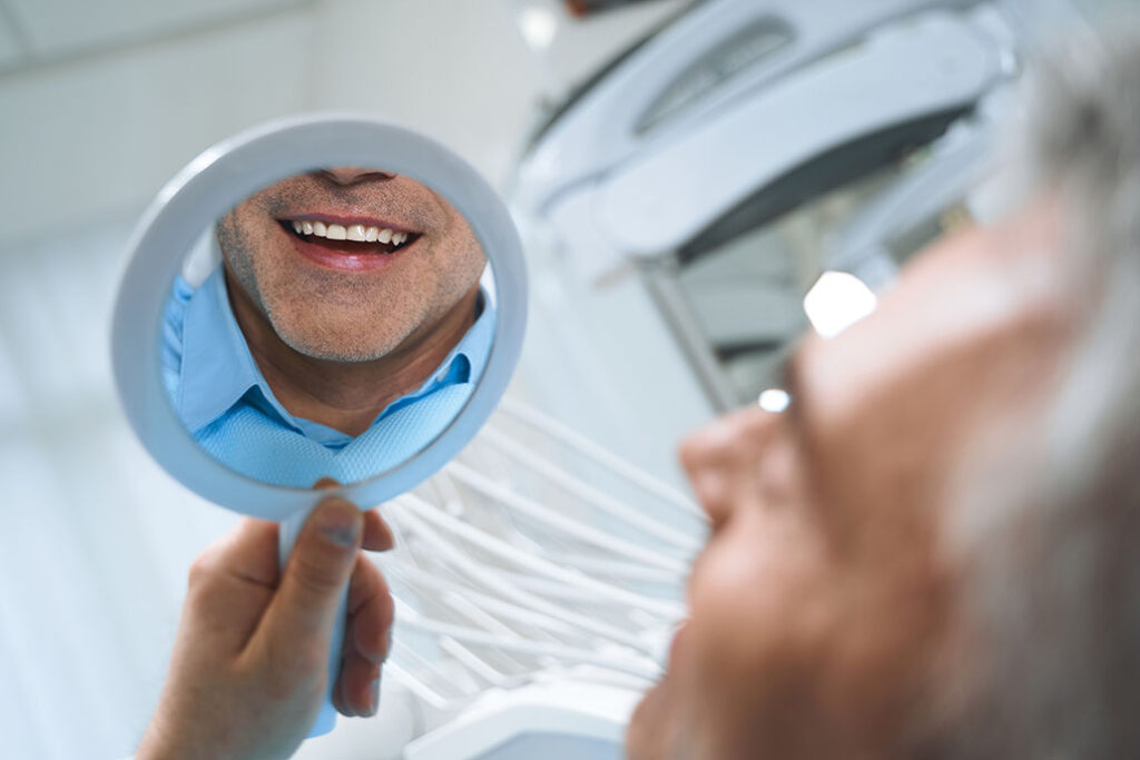 man smiling and looking at his dental implants