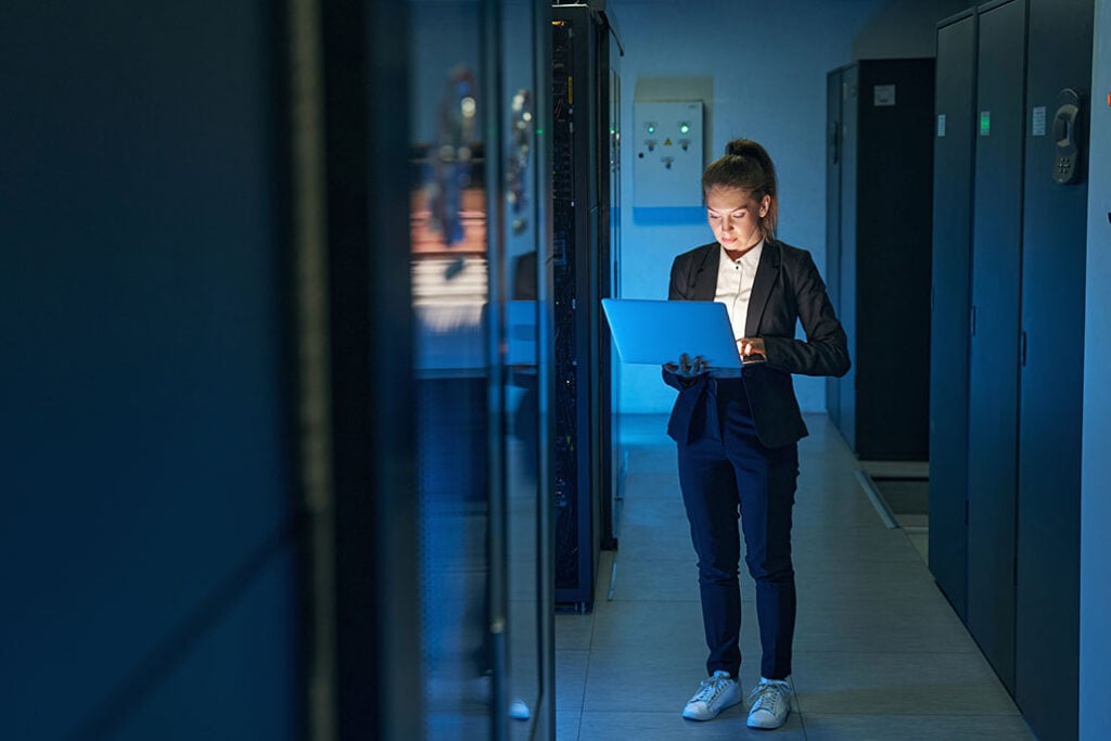 IT engineer use laptop computer while working with supercomputer in data center server room