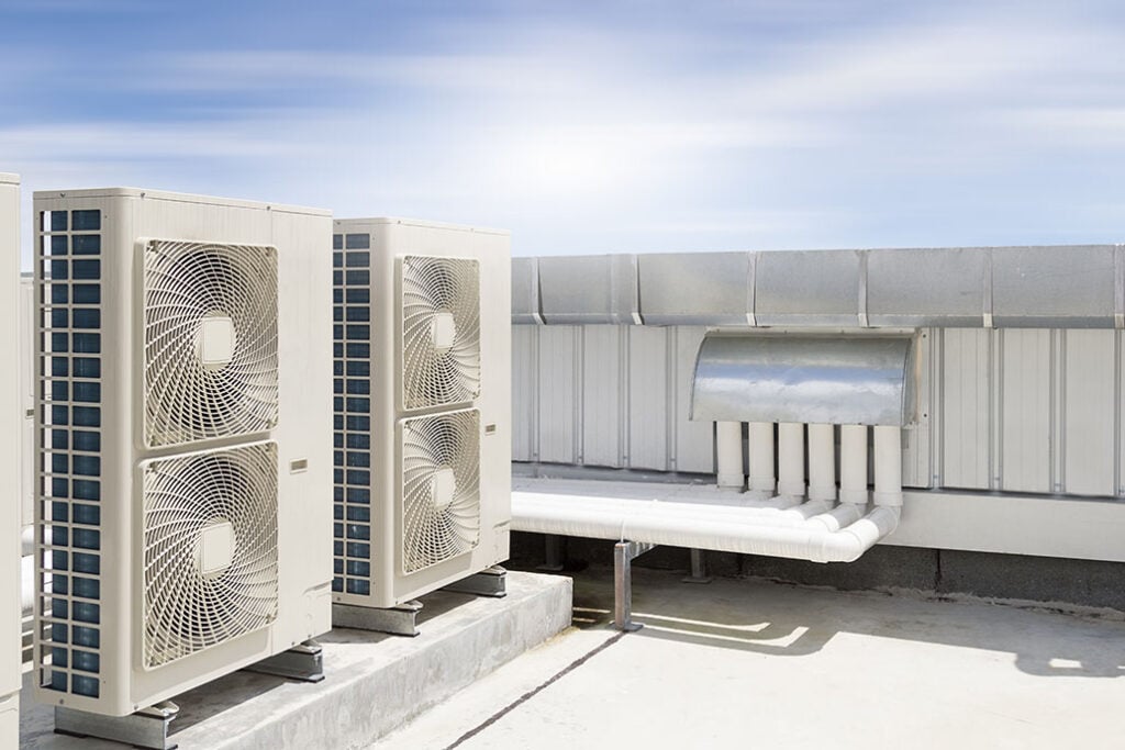 Air compressor machine part of air conditioner system on roof deck with sky background.