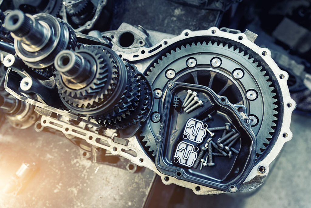 Closeup disassembled car automatic transmission gear part on workbench at garage or repair factory station for fix service or maintenance. Vehicle part detail. Complex industrial mechanism background.