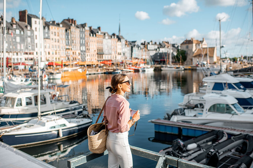 Young woman tourist enjoying beautiful view on the harbour traveling in Honfleur town in Normandy, France